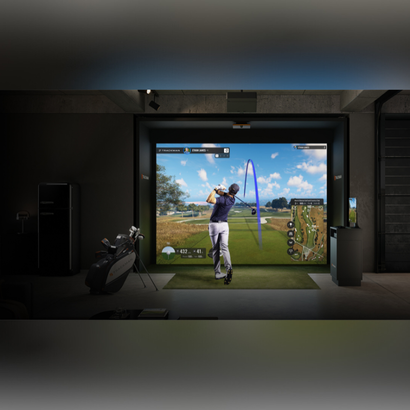 TrackMan IO Launch Monitor, vollständige Indoor-Golfsimulator-Aufstellung mit Launch Monitor, Leinwand, Projektor und Abschlagmatte in einem modernen Trainingsraum.